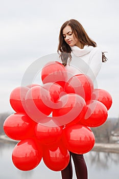 Young woman with red balloons, outdoors