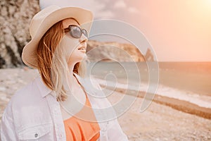 Young woman in red bikini on Beach. Blonde in sunglasses on pebble beach enjoying sun. Happy lady in one piece red