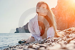 Young woman in red bikini on Beach. Girl lying on pebble beach and enjoying sun. Happy lady with long hair in bathing