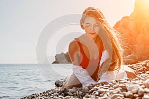 Young woman in red bikini on Beach. Girl lying on pebble beach and enjoying sun. Happy lady with long hair in bathing