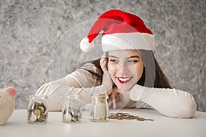 Young woman with red christmas hat looing at piggy bank photo