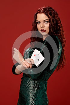 Young woman with a red curly hair holding aces, on a red background. Poker