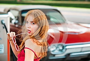 Young woman with red dress at the gas station. Attractive elegant girl refuel car on gas station.