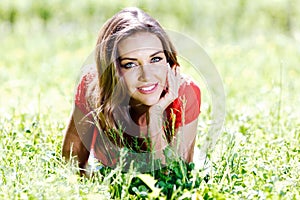 Young woman in red dress lying on grass