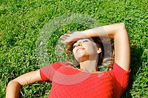 Young woman in red dress lying on grass