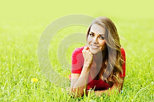 Young woman in red dress lying on grass