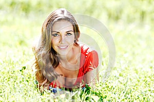 Young woman in red dress lying on grass