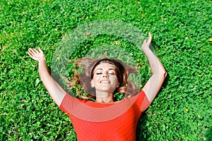 Young woman in red dress lying on grass