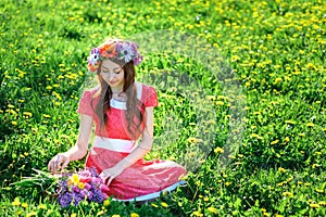 Young woman in a red dress lying on the grass in the Meadow