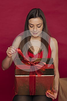 Young woman in a red dress opens a gift