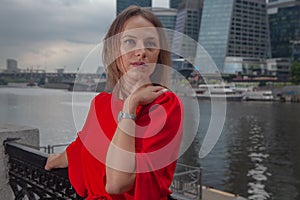 Young woman in red dress posing on city backround