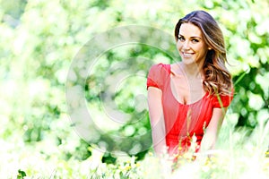 Young woman in red dress sitting on grass