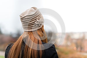 Young woman with red hair and beige hat from behind