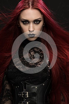 Young woman with red hair in black gothic costume