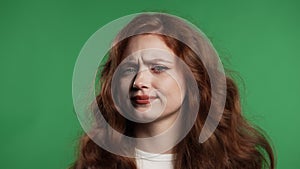 Young woman with red hair disapproving no head sign,nods disapprovingly on green