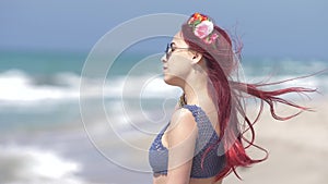 Young woman with red hair flying in the wind and a floral wreath in her hair against the background of the sea