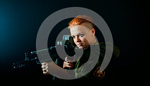 Young woman with red hair, hold machinegun in military uniform. horizontal background