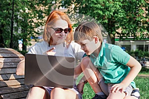 Young woman with red hair and laptop scolds her eight-year-old son for interfering with her work