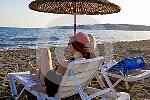 young woman in a red hat resting on the beach