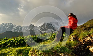 Young woman in red jacket enjoy sunset in mountains