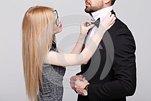 Young woman with red lips straighten man bow tie