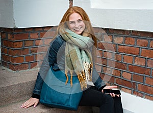 Young woman with red long hair smile and have a smartphone in her hand