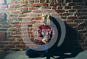 young woman in red pullover near the brick wall