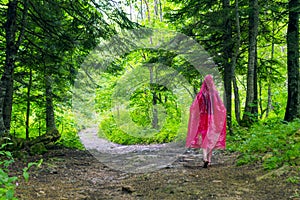 Young woman in a red raincoat walking in autumn