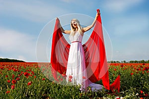 Young woman with red scarf in poppy field