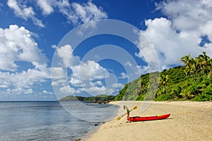 Young woman with red sea kayak on a sandy beach