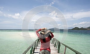 Young Woman with red shirt holding hat at beach for holiday