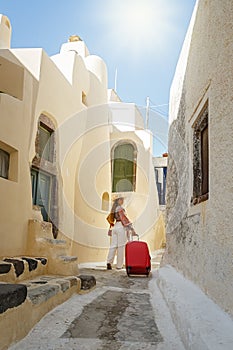 Young woman with a red suitcase on the background  Santorini, Greece