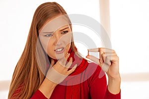 Young woman in red sweater holds pills in her hand as she is ill