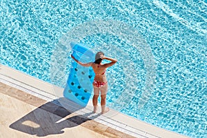 Young woman in red swimsuit stands on poolside