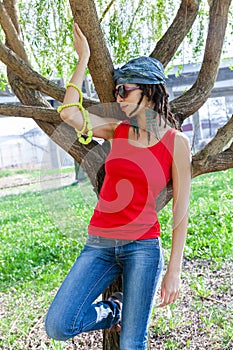 Young woman in red tank top with dreadlocks hairstyle and headscarf  and sunglasses outdoor spring day
