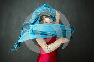 Young woman in red unitard waving a blue scarf.