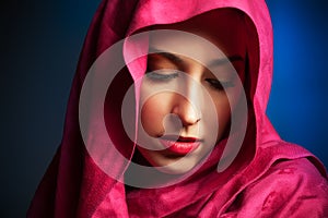 Young woman with red veil around her face