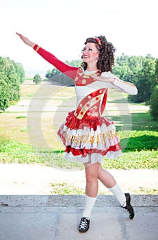 Young woman in red and white irish dance dress and wig posing