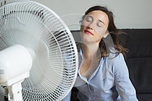 Mladá žena osviežujúci pred chladenie ventilátor 