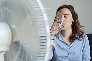 Young woman refreshing in front of cooling fan