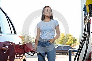 Young woman refueling car at self service gas station