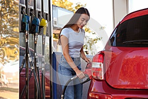 Young woman refueling car at self service gas station