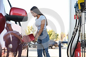 Young woman refueling car at self service gas station