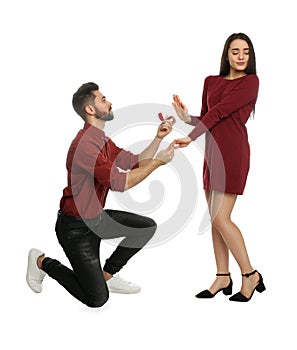 Young woman rejecting engagement ring from boyfriend on background