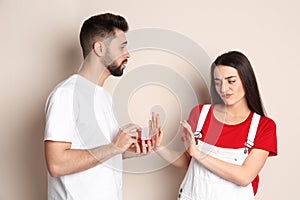 Young woman rejecting engagement ring from boyfriend on background