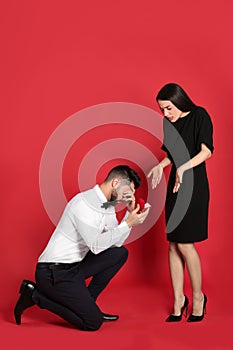 Young woman rejecting engagement ring from boyfriend on background