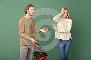 Young woman rejecting marriage proposal on color background