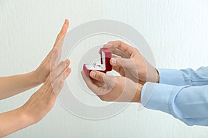 Young woman rejecting marriage proposal on light background