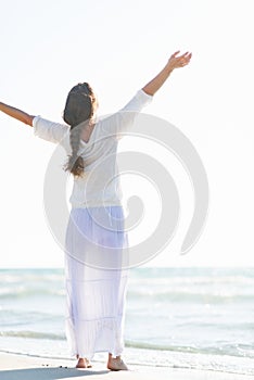 Young woman rejoicing on sea coast . rear view photo