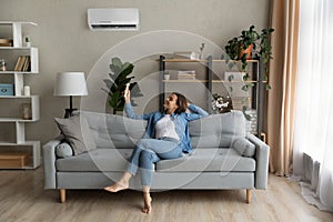 Young woman relax on couch turn on AC